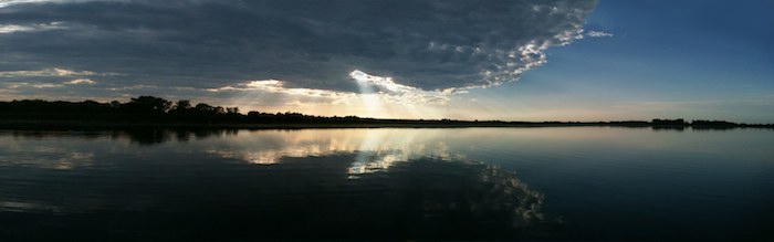 beams of light thru cloud near sunset over lake